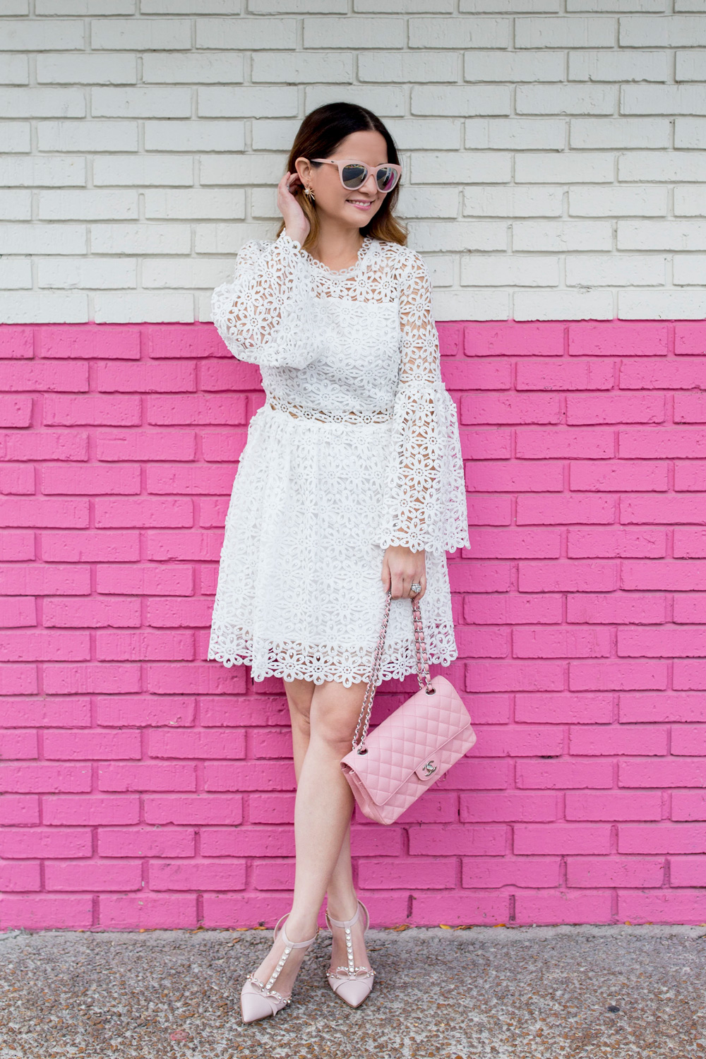 Jennifer Lake Style Charade wearing a white lace bell sleeve dress, Kate Spade Lydia heels, and pink Chanel quilted flap bag pink wall Chicago