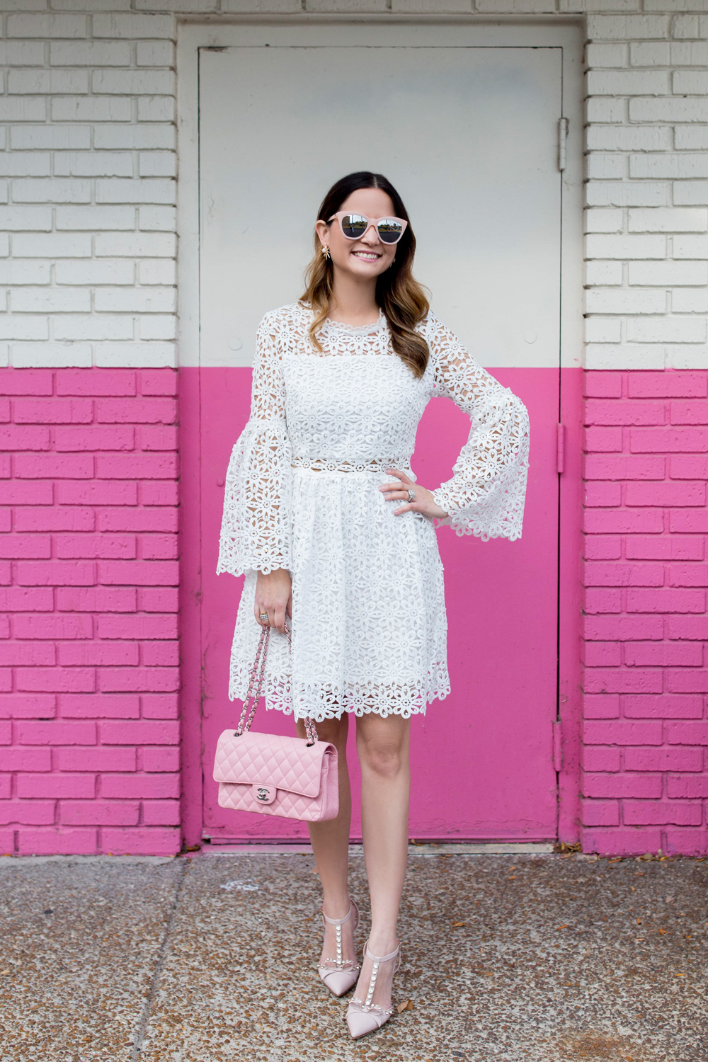 Jennifer Lake Style Charade wearing a white lace bell sleeve dress, Kate Spade Lydia heels, and pink Chanel quilted flap bag pink wall Chicago