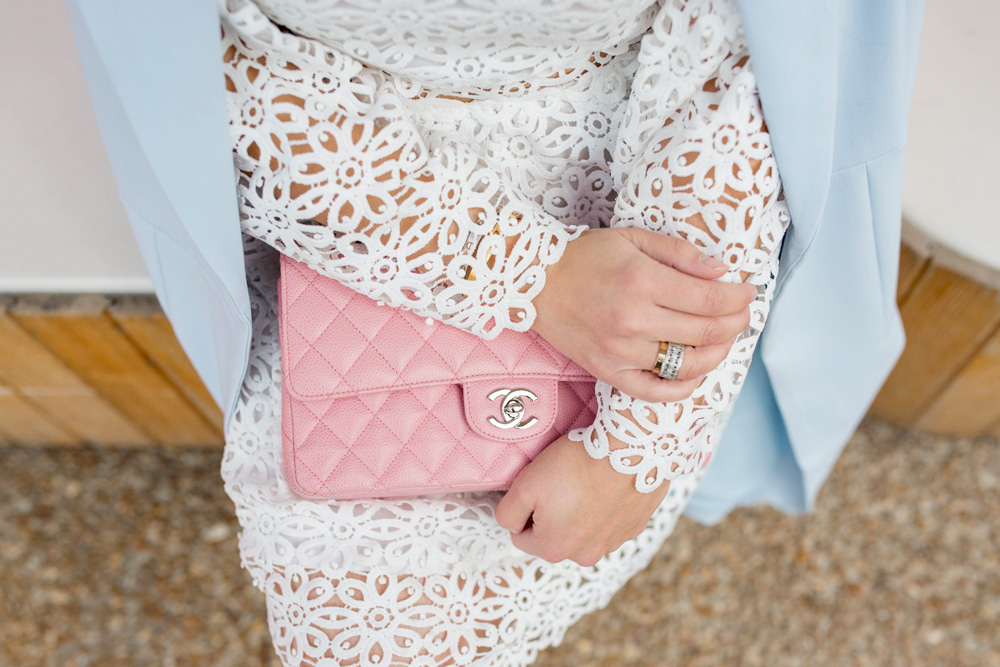 Jennifer Lake Style Charade wearing a white lace bell sleeve dress, long blue coat, and pink Chanel quilted flap bag, Cartier love ring