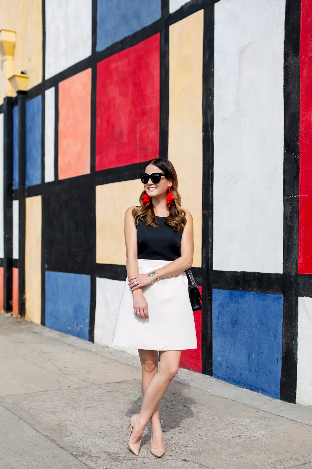 Jennifer Lake Style Charade in a black and white Kate Spade dress and a red Oscar de la Renta floral earrings at a colorful Mondrian wall mural in Los Angeles