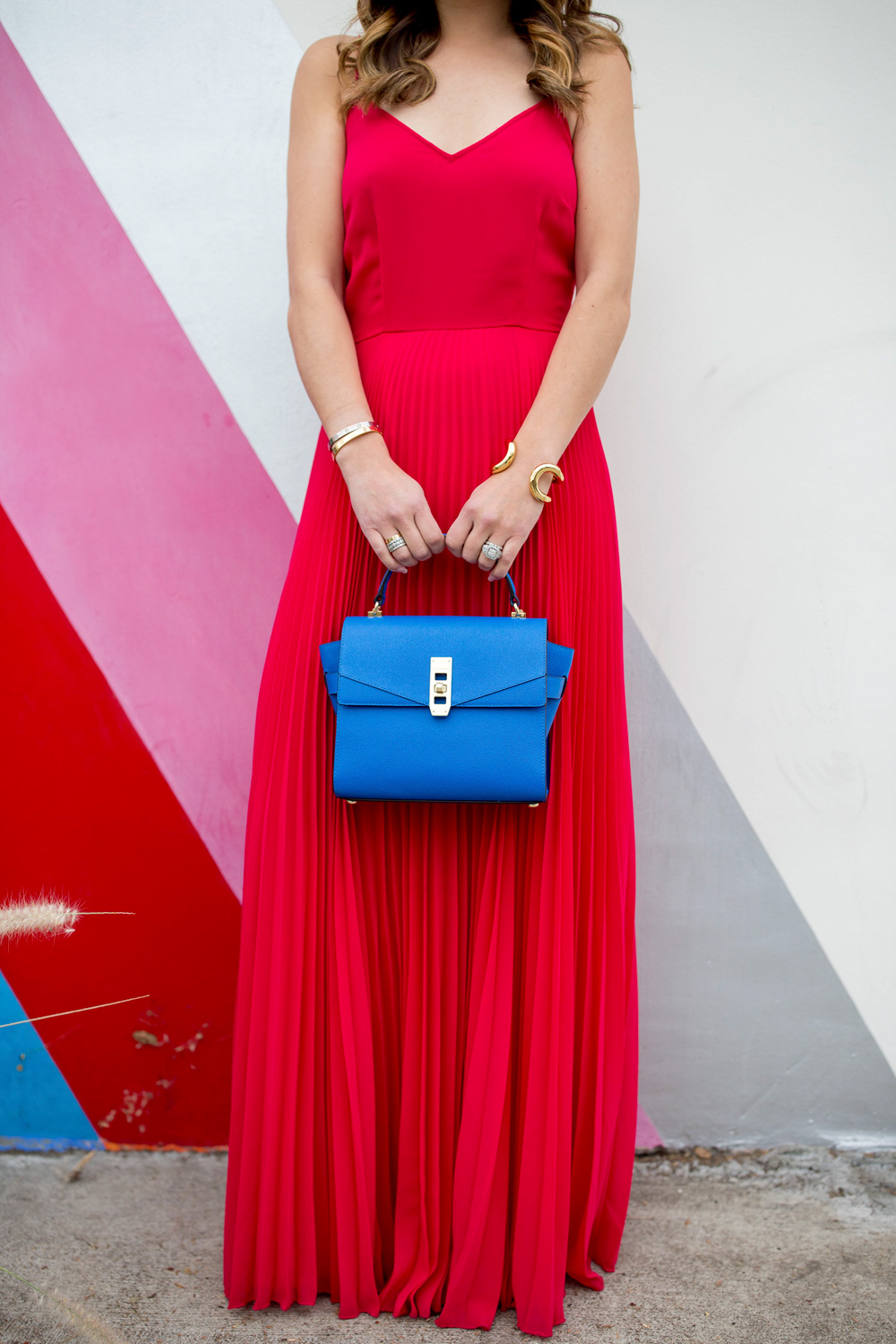 Jennifer Lake Style Charade in an ASOS pink maxi dress, blue Henri Bendel Mini Uptown satchel, and Giles and Brother Cortina cuff at a striped wall in Los Angeles