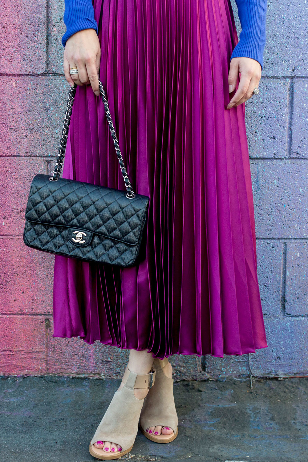 Jennifer Lake Style Charade in an ASOS purple pleated midi skirt, cobalt blue sweater bodysuit and Chanel quilted flap bag at a dripping paint wall in Los Angeles