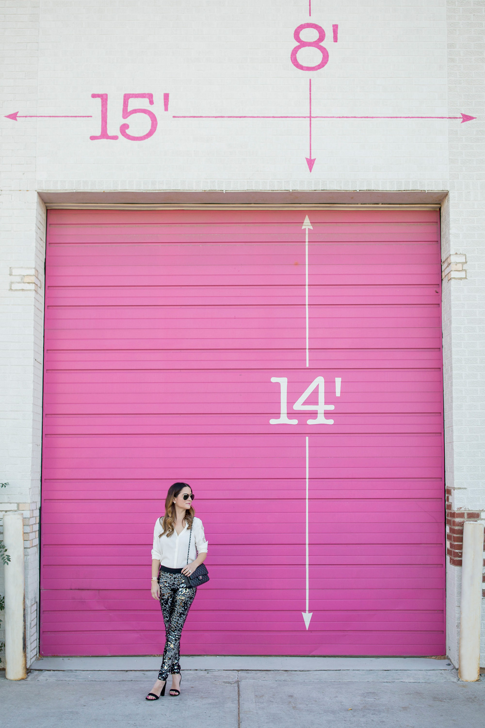 Jennifer Lake Style Charade in Express sequin leggings, ivory lace top, and a quilted Chanel flap bag in front of a Chicago pink wall