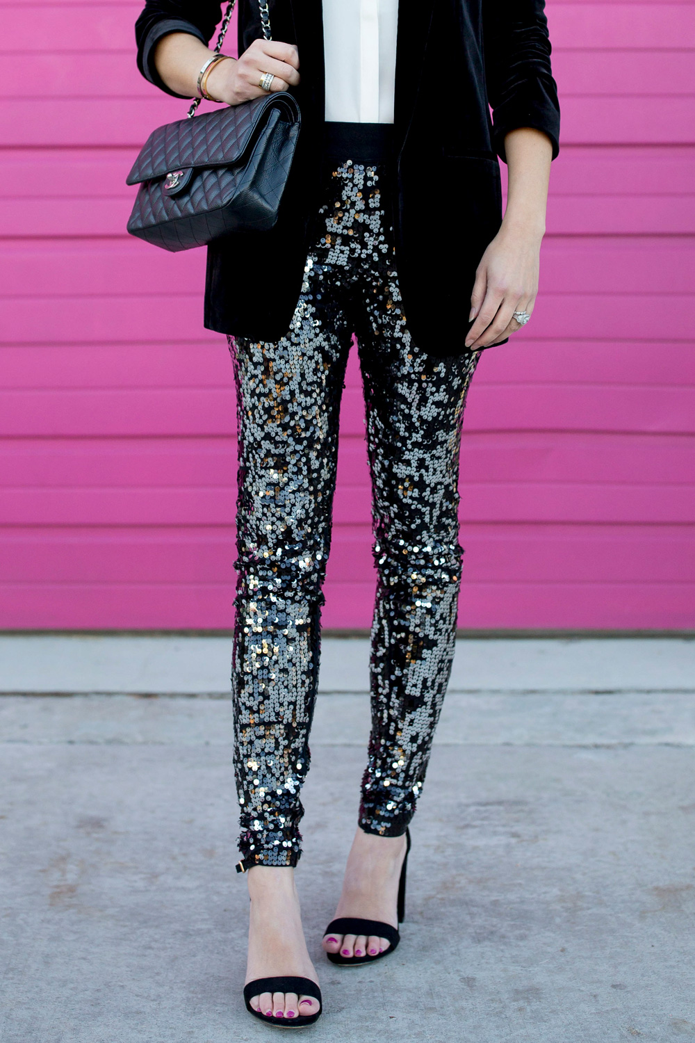 Jennifer Lake Style Charade in Express sequin leggings, black velvet blazer, ivory lace top, and a quilted Chanel flap bag in front of a Chicago pink wall