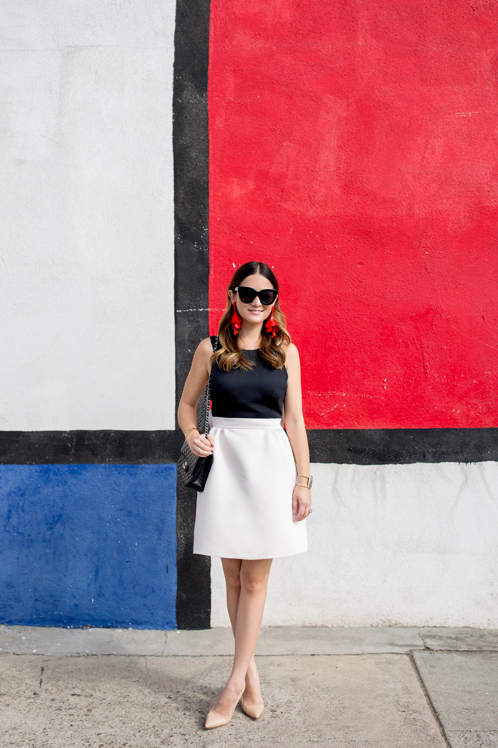 Jennifer Lake Style Charade in a black and white Kate Spade bow dress and a red Oscar de la Renta floral earrings at a colorful Mondrian wall mural in Los Angeles