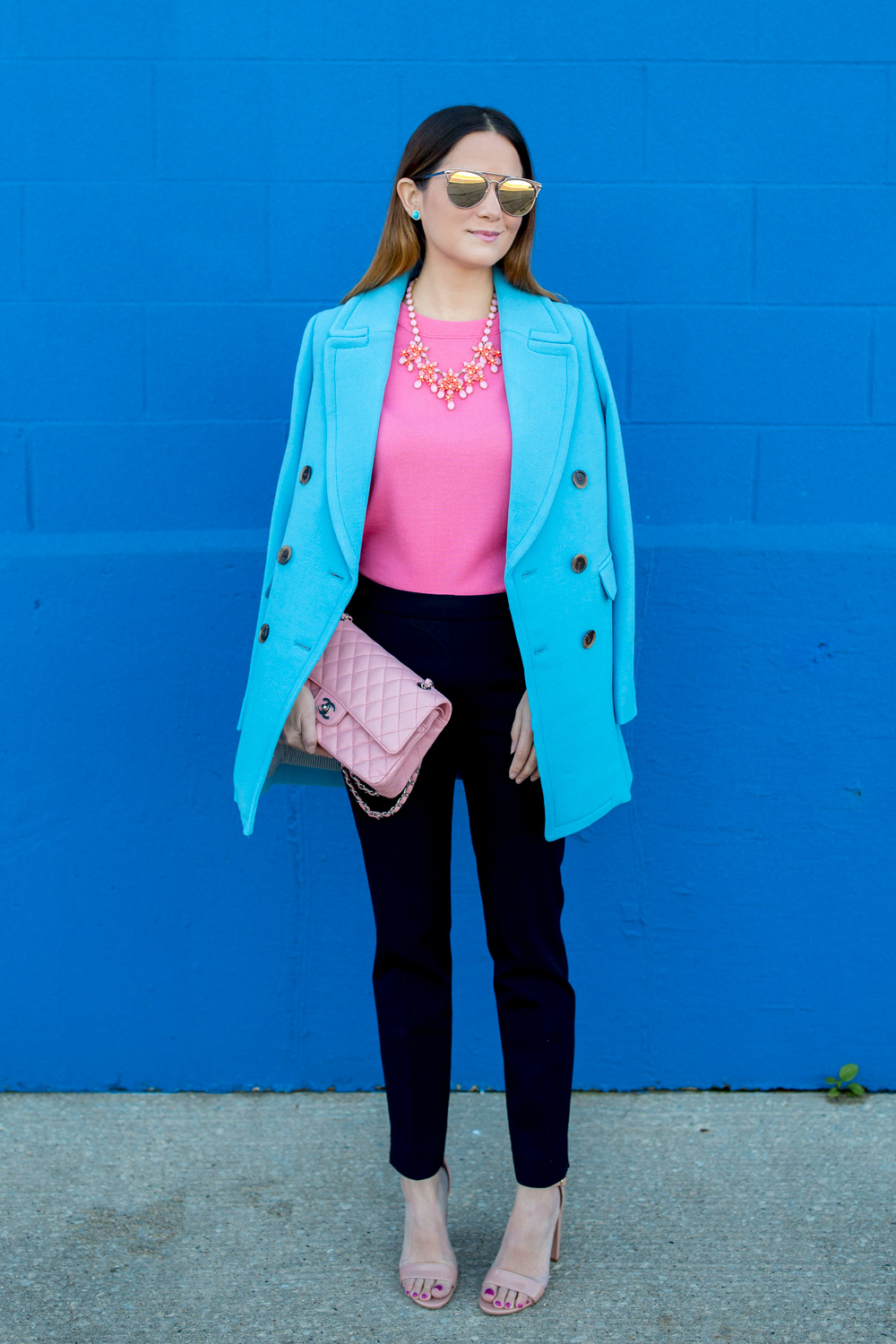 Jennifer Lake Style Charade in J Crew Nordstrom blue coat, pink cashmere sweater, pink Chanel quilted flap bag, and Steve Madden Carrson sandals at a blue wall in Chicago