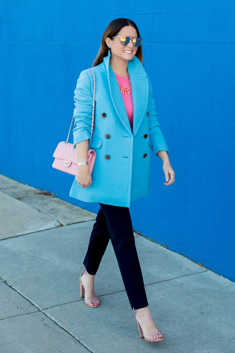 Jennifer Lake Style Charade in J Crew Nordstrom blue coat, pink cashmere sweater, pink Chanel quilted flap bag, and Steve Madden Carrson sandals at a blue wall in Chicago