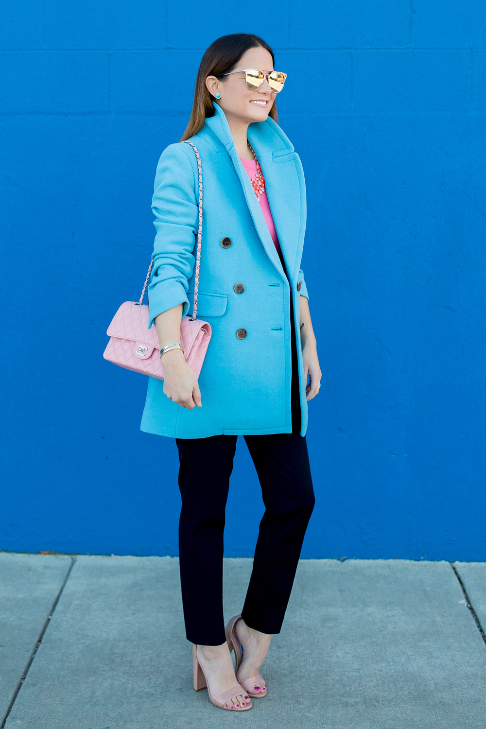 Jennifer Lake Style Charade in J Crew Nordstrom blue coat, pink cashmere sweater, pink Chanel quilted flap bag, and Steve Madden Carrson sandals at a blue wall in Chicago