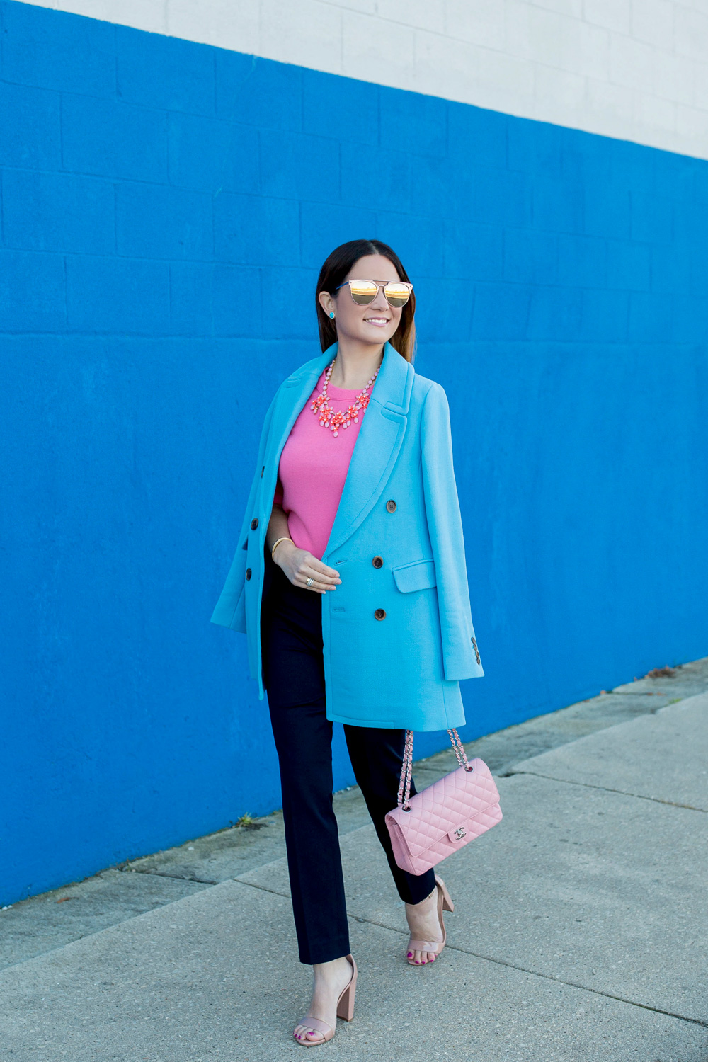 Jennifer Lake Style Charade in J Crew Nordstrom blue coat, pink cashmere sweater, pink Chanel quilted flap bag, and Steve Madden Carrson sandals at a blue wall in Chicago