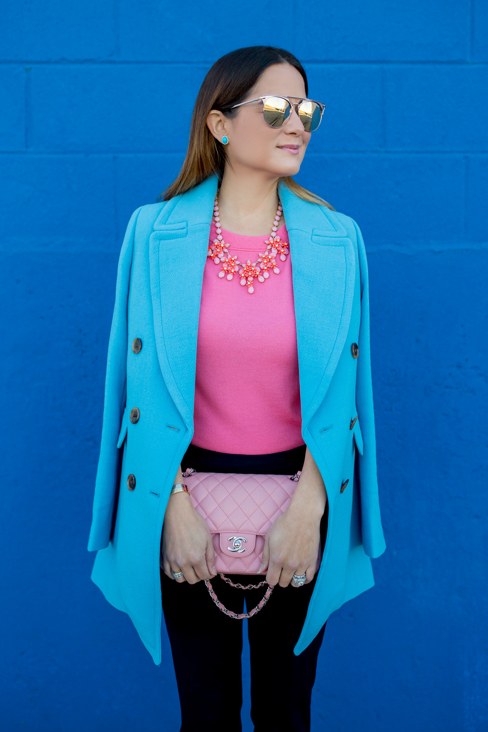 Jennifer Lake Style Charade in J Crew Nordstrom blue coat, pink cashmere sweater, pink Chanel quilted flap bag, and Steve Madden Carrson sandals at a blue wall in Chicago