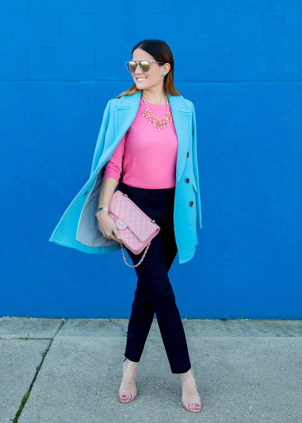 Jennifer Lake Style Charade in J Crew Nordstrom blue coat, pink cashmere sweater, pink Chanel quilted flap bag, and Steve Madden Carrson sandals at a blue wall in Chicago