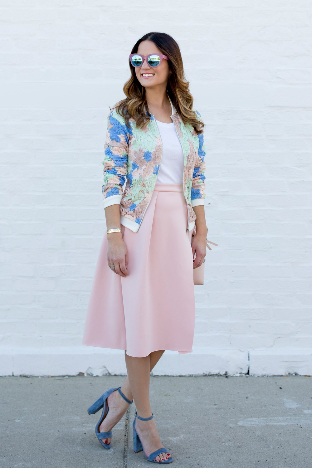 Jennifer Lake Style Charade in a pastel lace bomber jacket, pink skirt, pink Mansur Gavriel Bucket bag, and Packed Party Toms sunglasses