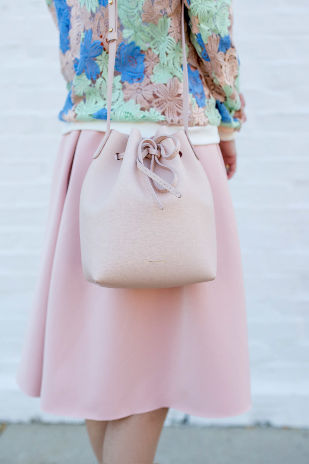 Jennifer Lake Style Charade in a Nordstrom pastel lace bomber jacket, pink skirt, and a pink Mansur Gavriel bucket bag